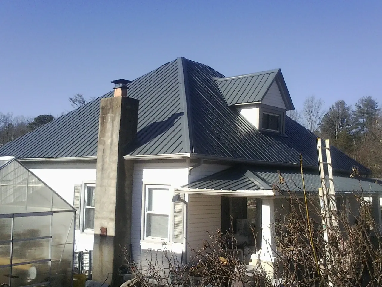 Dark blue standing seam metal roof on a white farmhouse with dormer — Slate & Tile Roof Repair by Roofing Brothers in Weeping Water