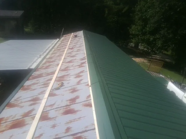 Old rusted panels beside newly installed green metal roofing — Wind Damage Roof Repair by Roofing Brothers in Weeping Water