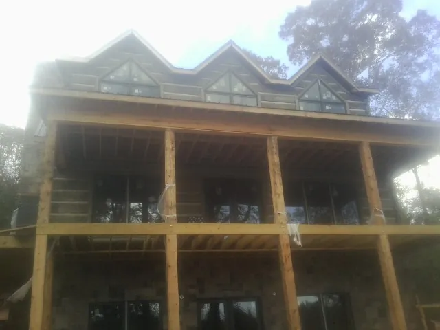 Dormers and porch framing on a large log home under construction — Roof Coating work by our crew in Weeping Water