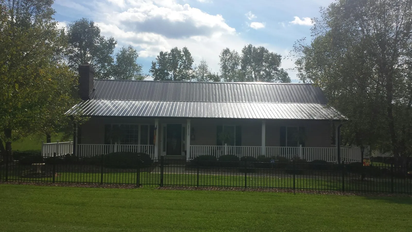 Gray metal roof on a brick ranch with a full width front porch — Gutter Guard Installation work by our crew in Weeping Water