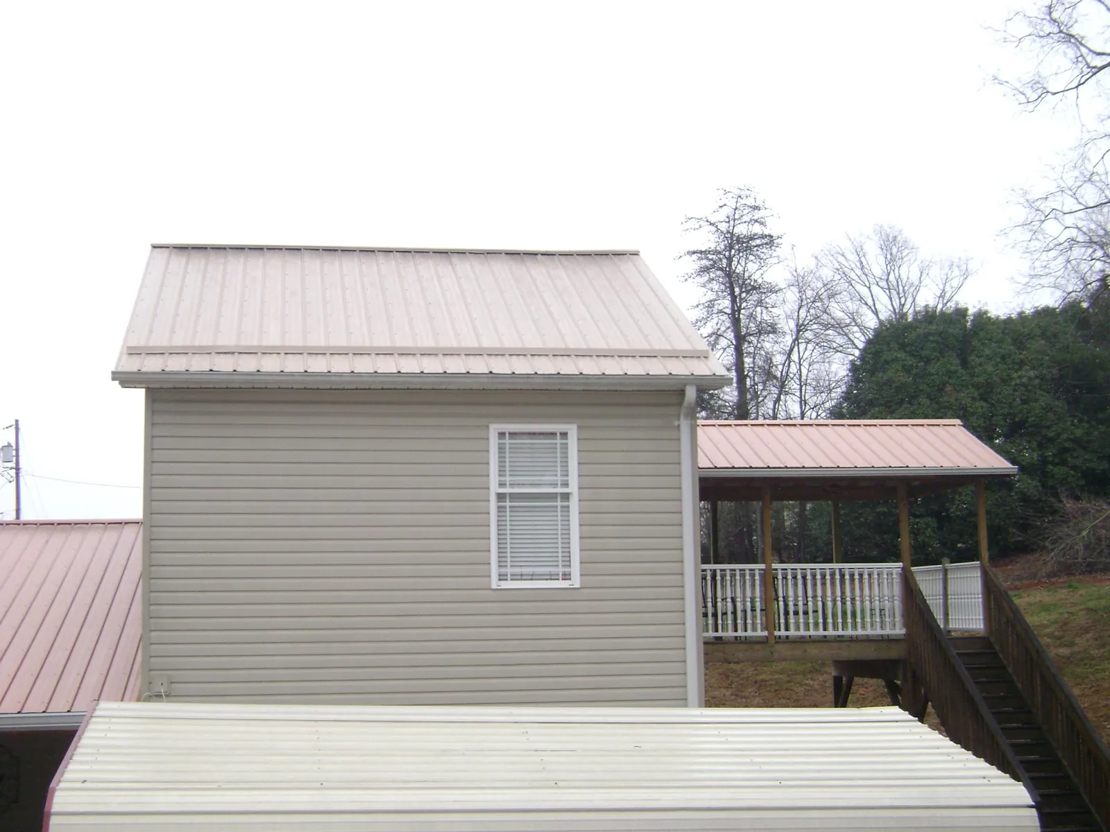 Tan metal roofs on a two story addition and attached porch, from a Roof Replacement job in Weeping Water