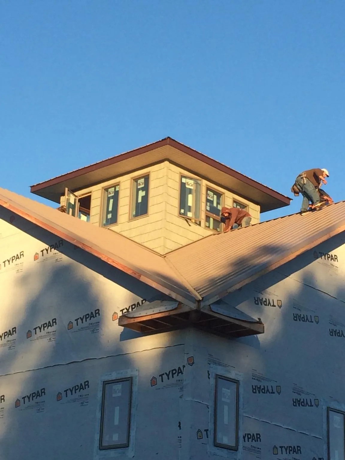 Roofers working around a rooftop cupola on a new metal roof at sunset — Roof Waterproofing in Weeping Water by Roofing Brothers